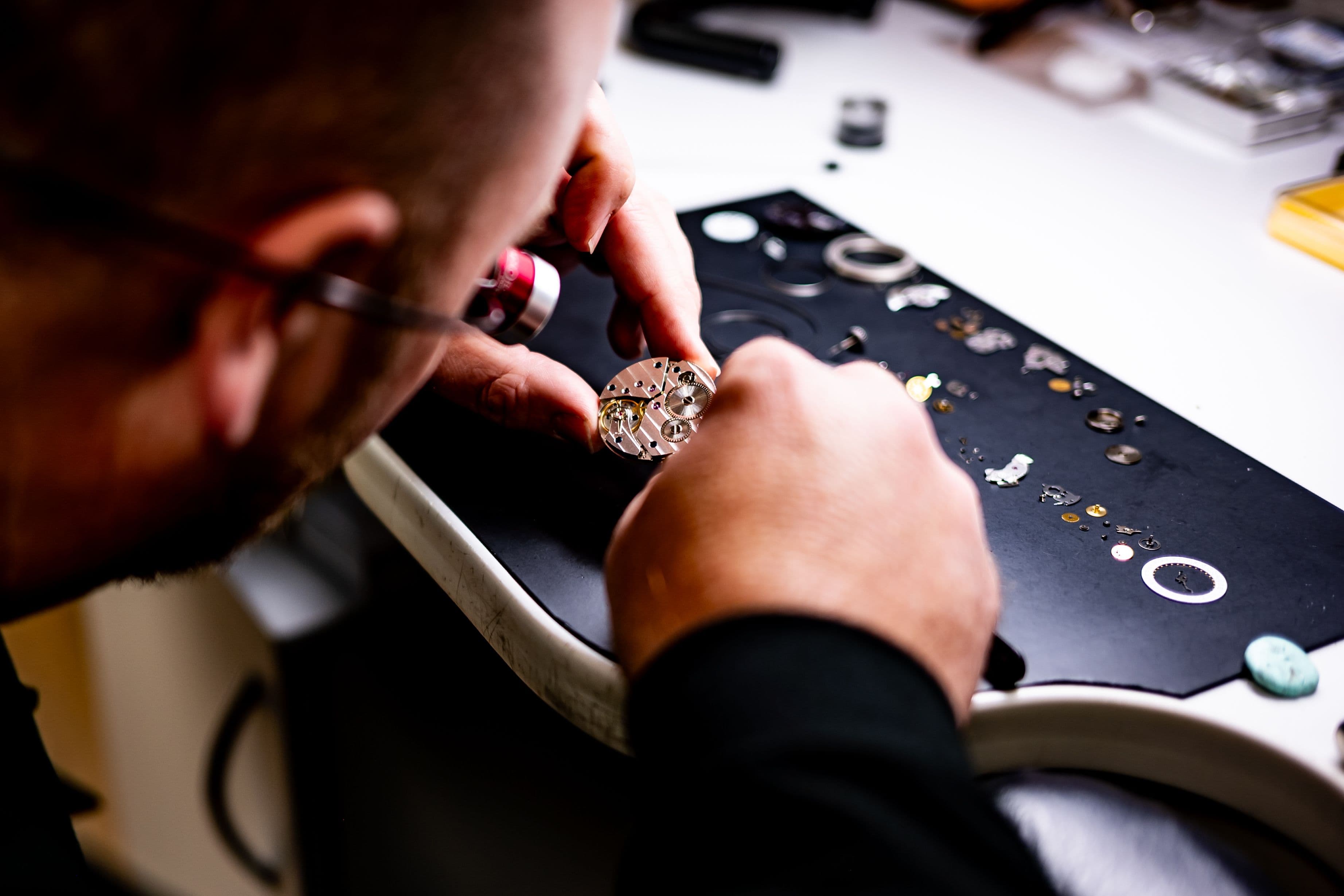 Close-up of hands assembling a small mechanical watch movement